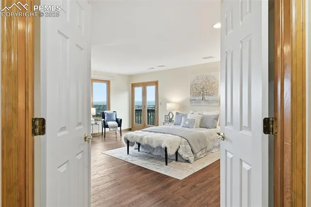 a bedroom with a bed and large windows with wooden floor