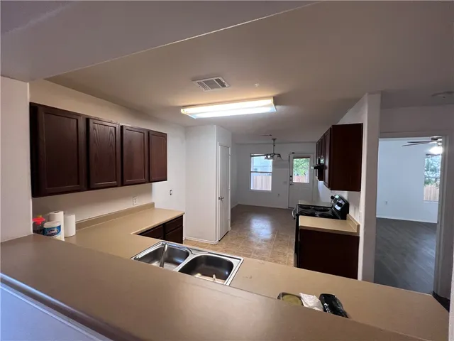 a living room with stainless steel appliances kitchen island granite countertop a refrigerator and a stove with wooden floor