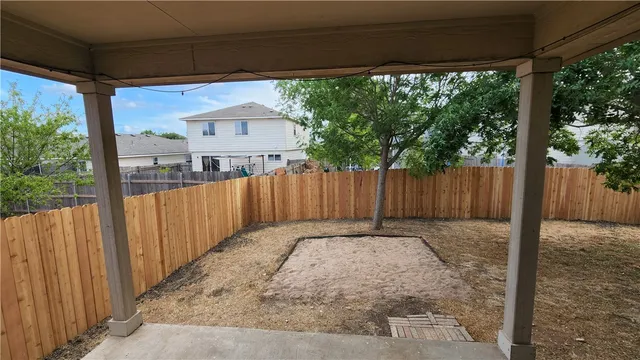 a view of a backyard with wooden fence and a porch
