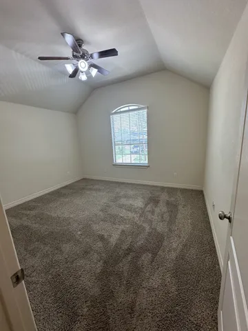 an empty room with a chandelier fan and windows