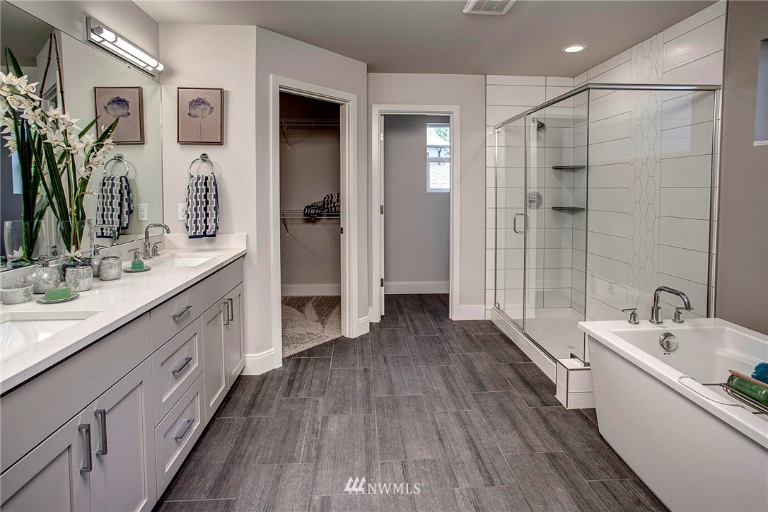 22212 17th Avenue West, Unit 5 Bothell, WA 98021 - Photo 26 of 37 a bathroom with a double vanity sink a large mirror a bathtub and shower