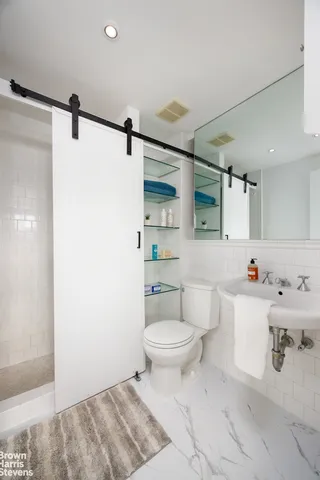 a bathroom with a toilet sink vanity granite and shower