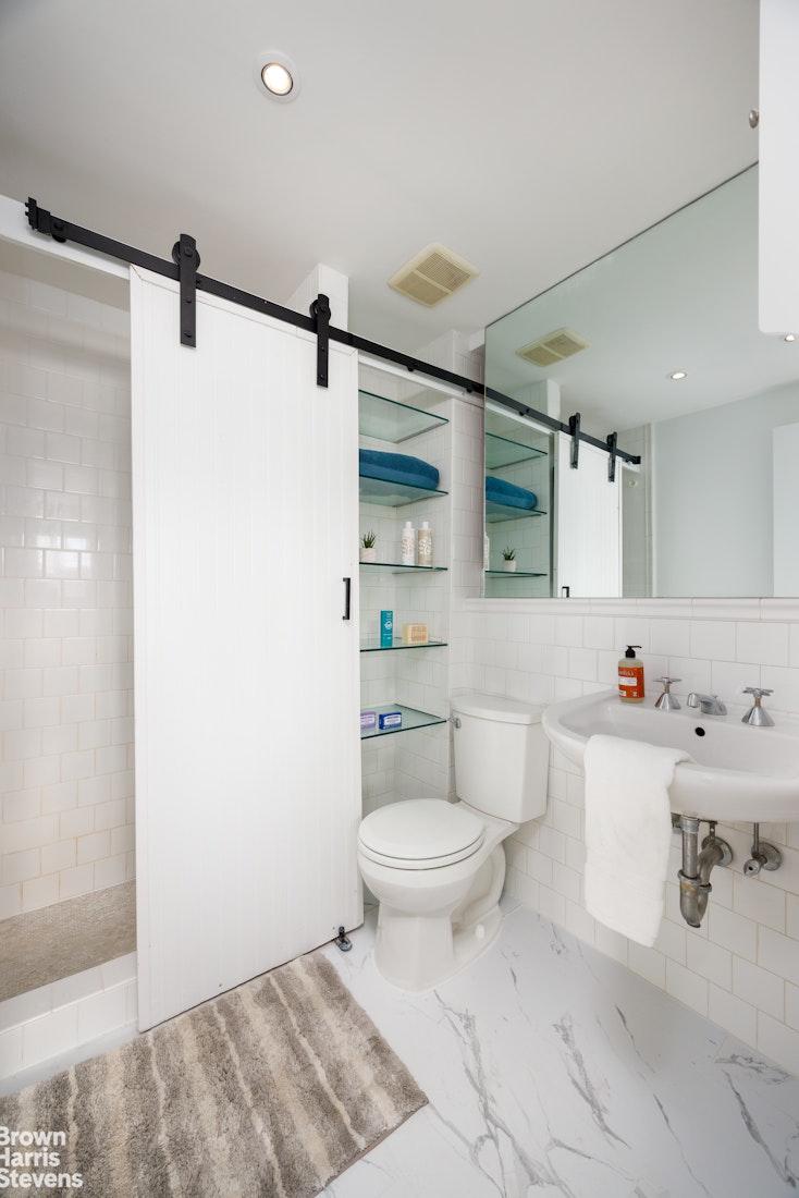 40 West 17th Street, Unit 12A Manhattan, NY 10011 - Photo 12 of 22 a bathroom with a toilet sink vanity granite and shower