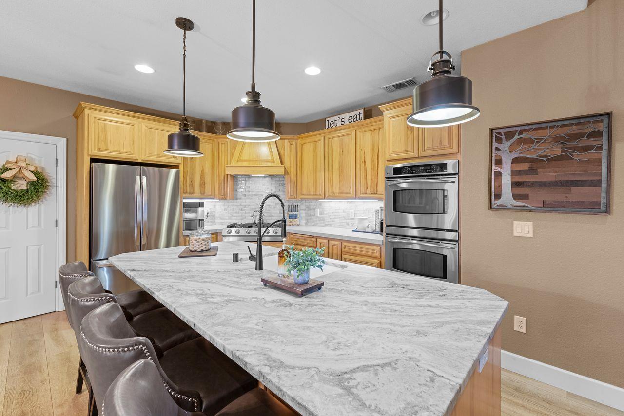 3302 Bear River Drive Rio Oso, CA 95674 - Photo 11 of 50 a kitchen with granite countertop a table chairs stainless steel appliances and wooden floor