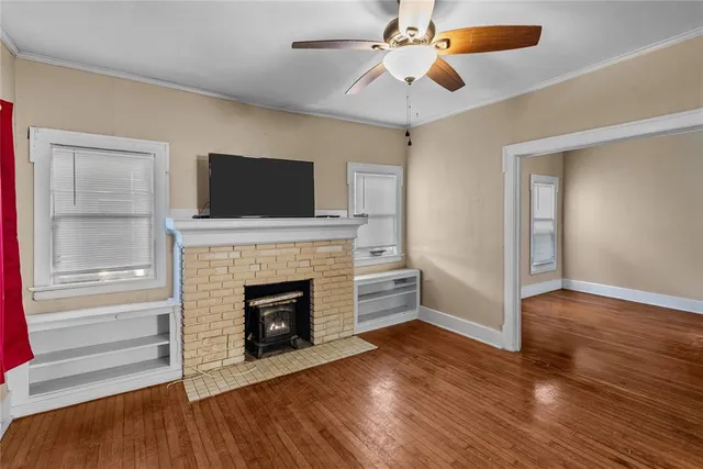 an empty room with windows a fireplace and wooden floor
