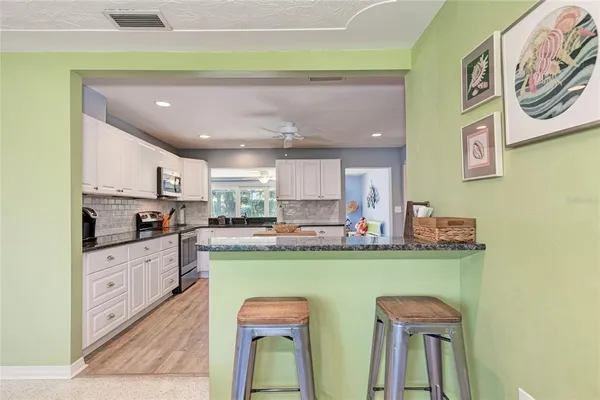 a kitchen with stainless steel appliances granite countertop a refrigerator a sink dishwasher a stove with wooden cabinets and floor