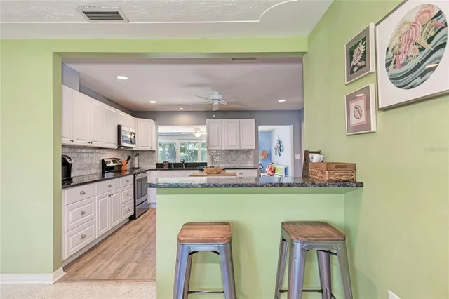 a kitchen with stainless steel appliances granite countertop a refrigerator a sink dishwasher a stove with wooden cabinets and floor