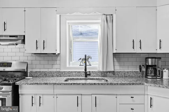 a kitchen with granite countertop white cabinets and a sink