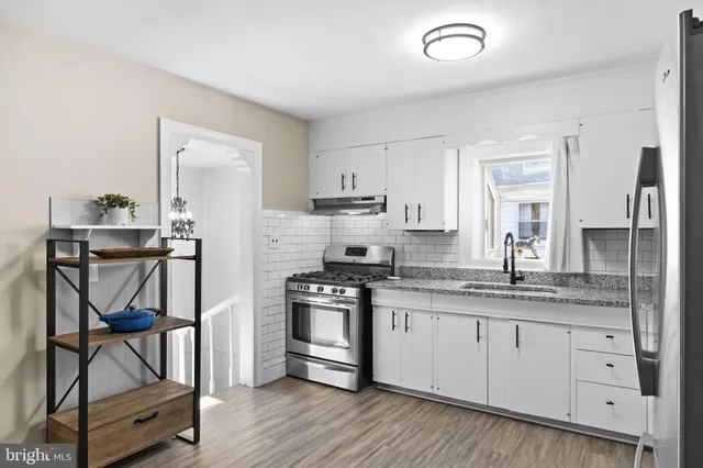 a kitchen with stainless steel appliances granite countertop a stove and white cabinets with wooden floor