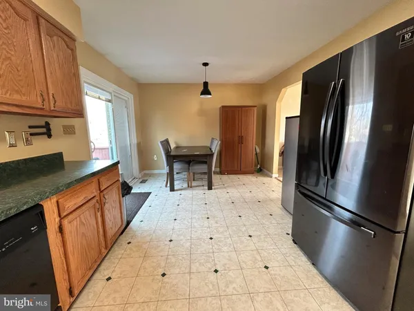 a kitchen with stainless steel appliances granite countertop a refrigerator a sink dishwasher a stove top oven a dining table and chairs with wooden floor