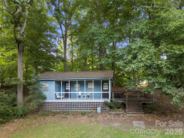 a view of a house with a yard and large trees