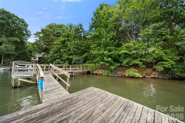 a view of a wooden deck and lake with trees in the background