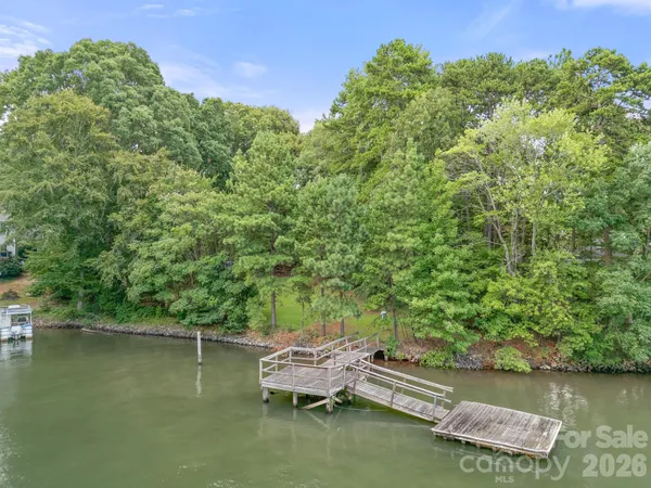 a view of a lake with lawn chairs and wooden fence