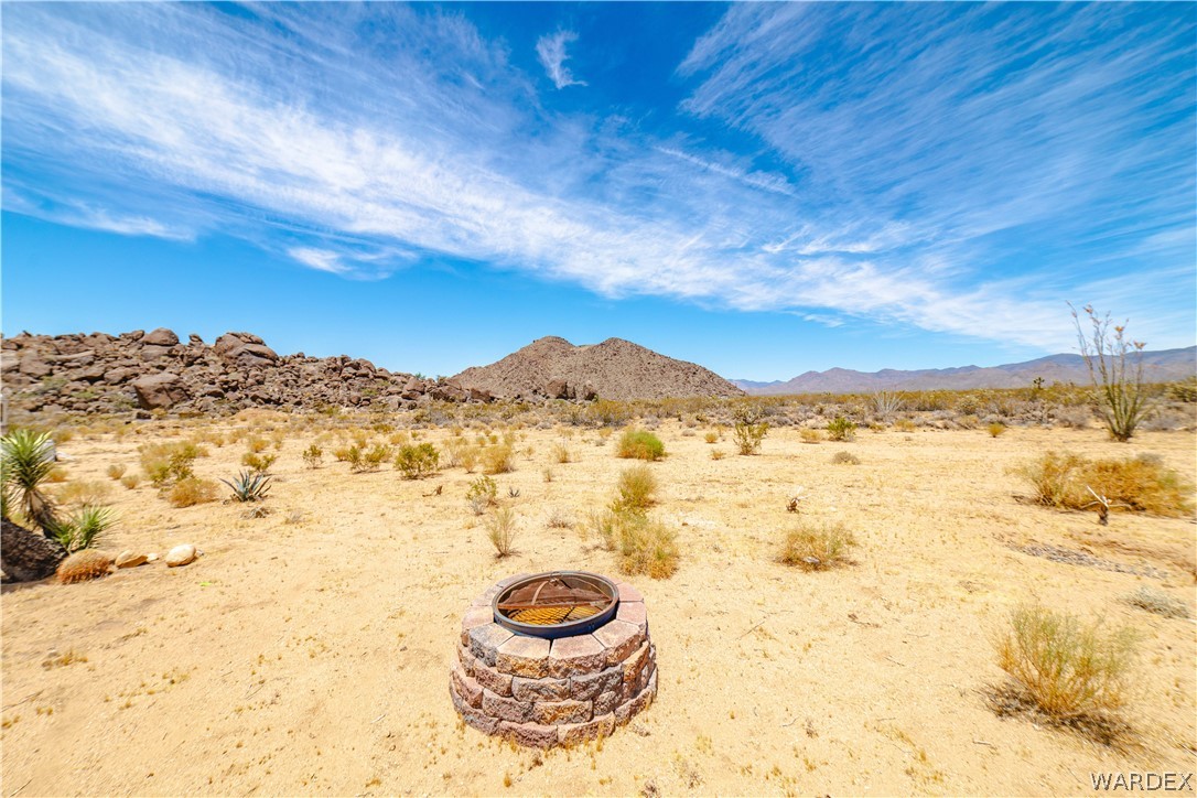 16435 South Wyatt Earp Road Yucca, AZ 86438 - Photo 34 of 57 Desert landscape featuring a stone-clad fire pit