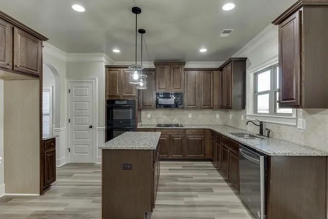 a kitchen with stainless steel appliances granite countertop wooden cabinets a refrigerator and a sink