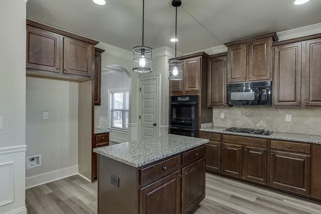 a kitchen with kitchen island granite countertop a sink and refrigerator