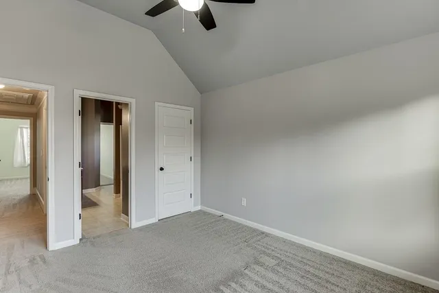 an empty room with chandelier fan and windows