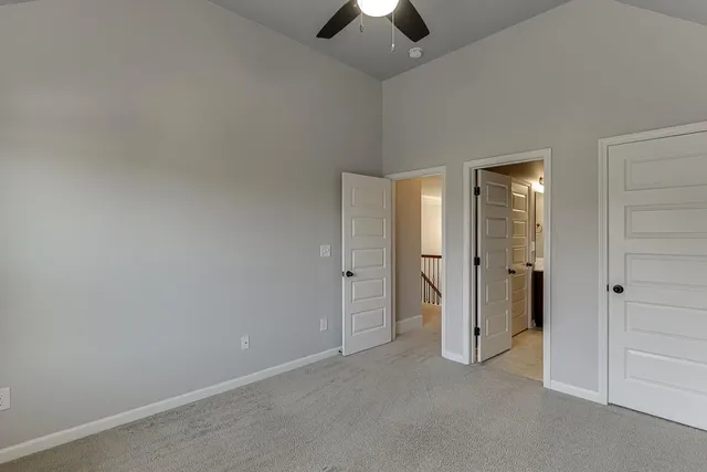 an empty room with chandelier fan and closet area