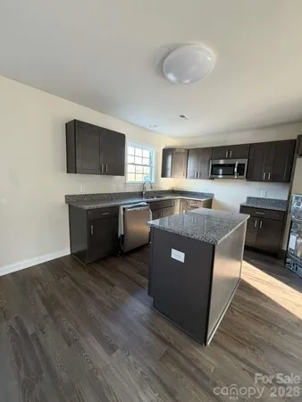 a kitchen with stainless steel appliances granite countertop a stove a sink and a microwave