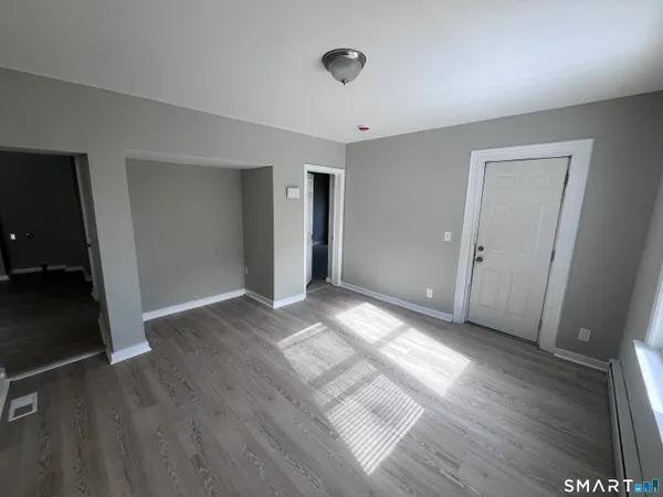 an empty room with wooden floor and windows