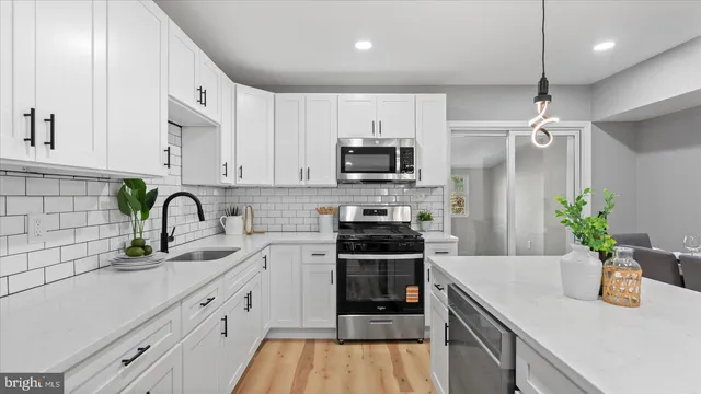 a kitchen with kitchen island white cabinets a sink a stove and wooden floors