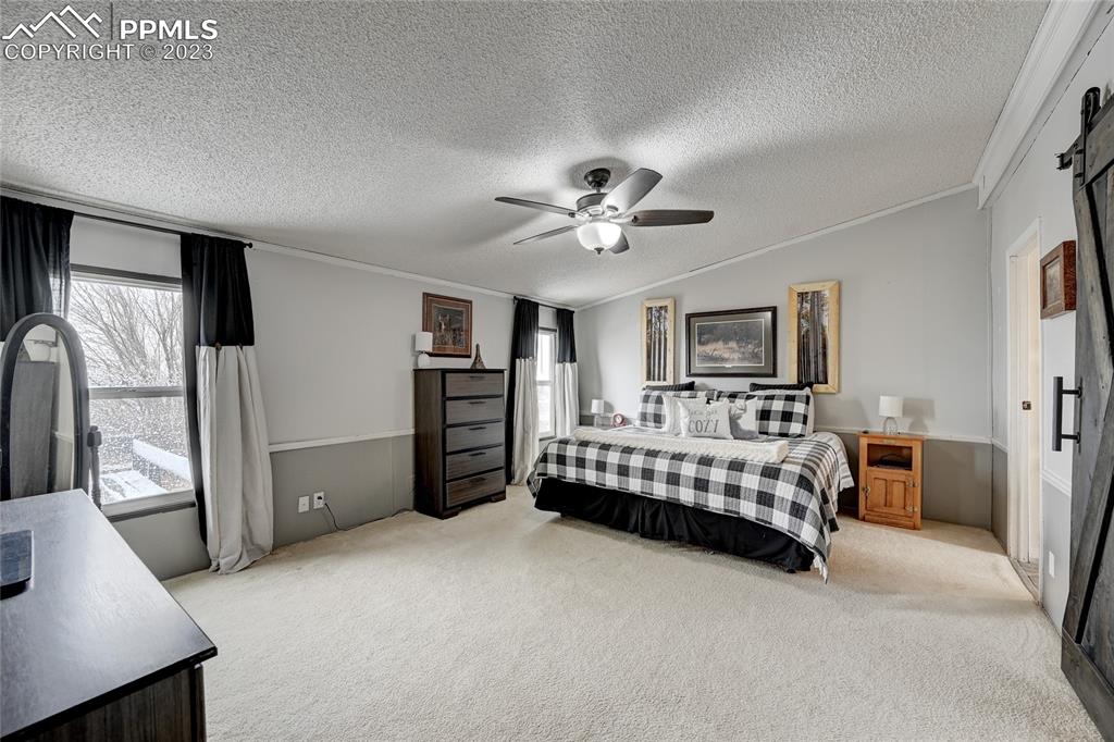 237 9th Street Penrose, CO 81240 - Photo 12 of 24 a spacious bedroom with a bed and a chandelier
