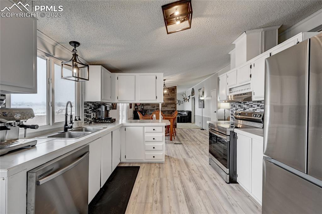 237 9th Street Penrose, CO 81240 - Photo 9 of 24 a kitchen with white cabinets and stainless steel appliances