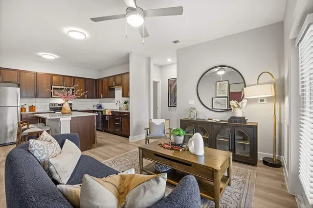 a living room with furniture a rug kitchen view and a chandelier