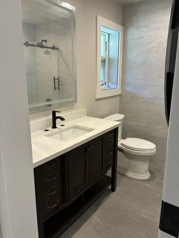 a bathroom with a sink a toilet a mirror and shower