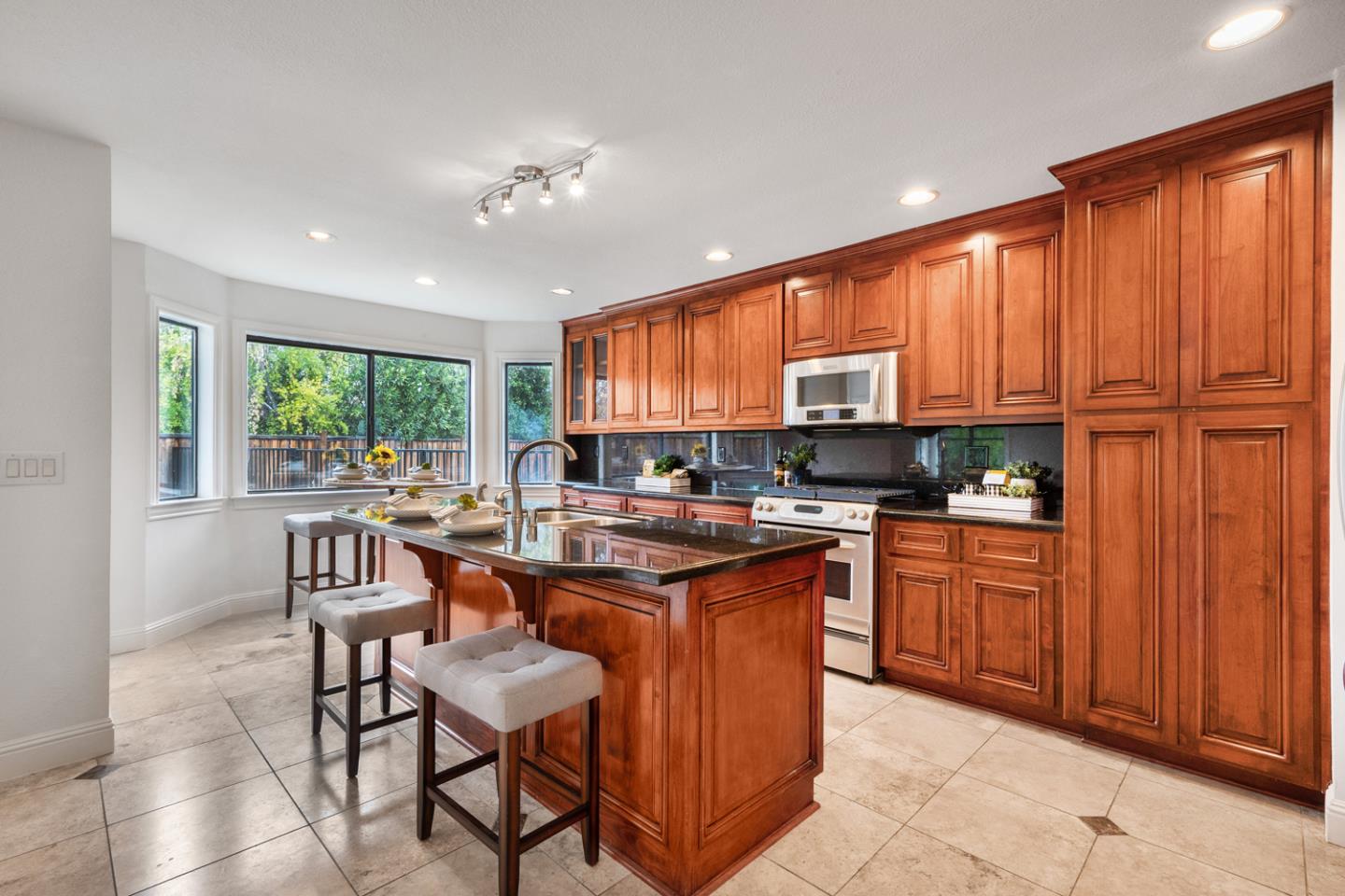 9040 Ridgeway Drive Gilroy, CA 95020 - Photo 15 of 44 a kitchen with stainless steel appliances granite countertop wooden cabinets a table and chairs