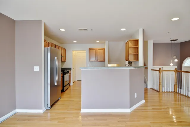 a living room with stainless steel appliances kitchen island granite countertop a refrigerator a stove and a sink with wooden floor