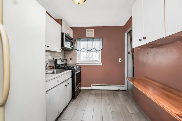 a kitchen with granite countertop a sink cabinets stainless steel appliances and a window