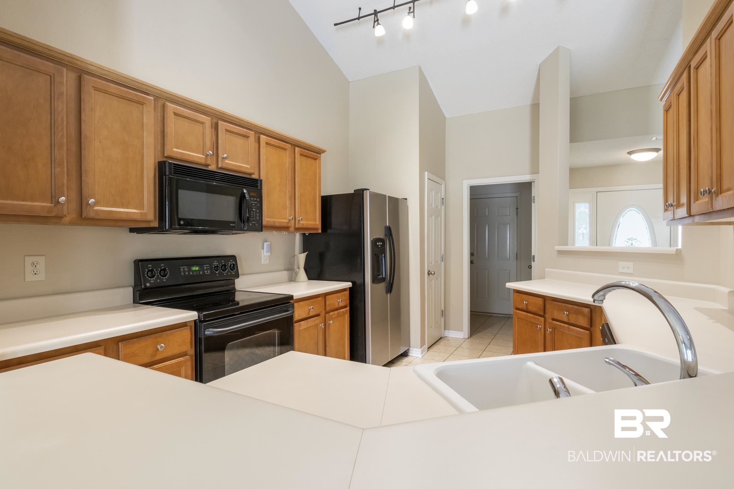 9610 Watkins Drive Fairhope, AL 36532 - Photo 6 of 26 Kitchen featuring track lighting, black appliances, vaulted ceiling, sink, and light tile patterned floors