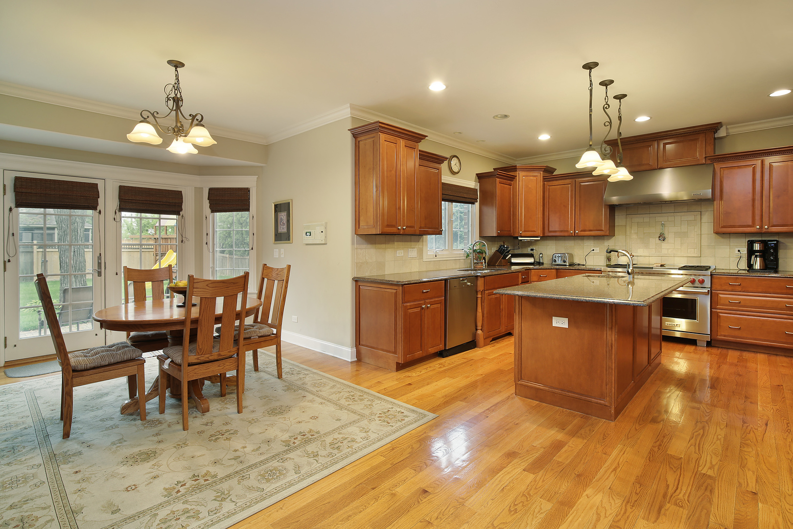 1528 Stratford Road Deerfield, IL 60015 - Photo 6 of 25 a kitchen with stainless steel appliances granite countertop a stove top oven a sink dishwasher a dining table and chairs with wooden floor