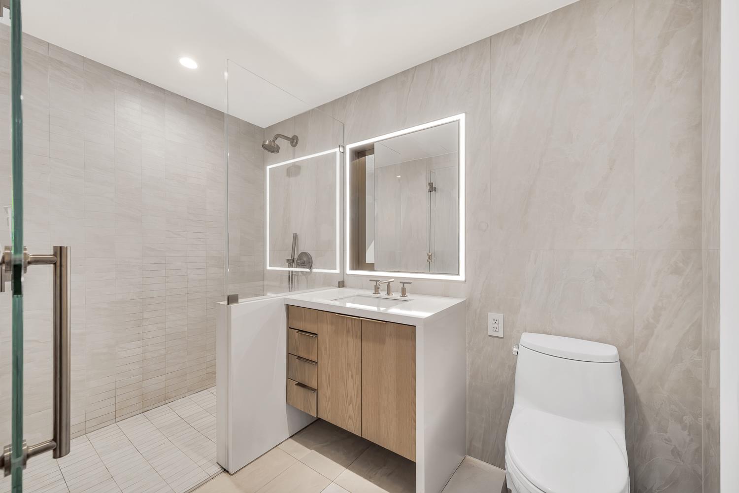 3 Court Square, Unit 902 Queens, NY 11101 - Photo 6 of 11 a bathroom with a toilet a sink a vanity and mirror