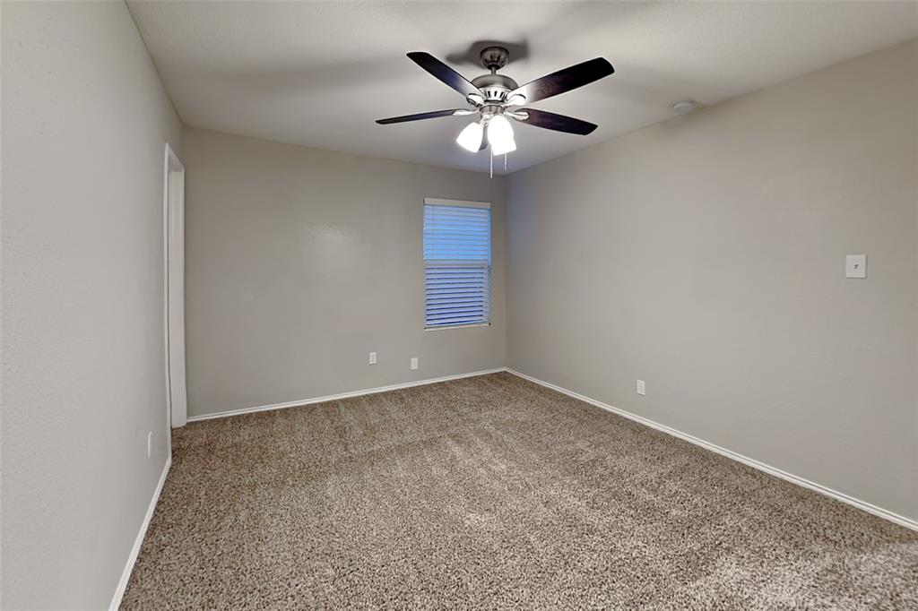 5529 McClelland Street Forney, TX 75126 - Photo 12 of 16 an empty room with a chandelier fan and windows