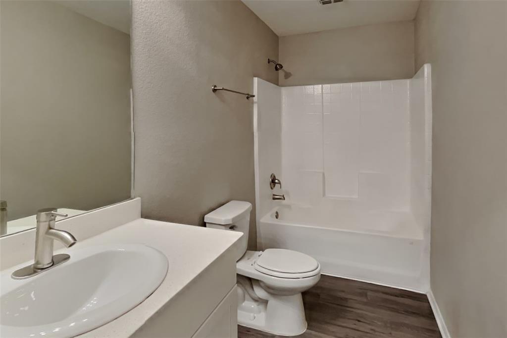 5529 McClelland Street Forney, TX 75126 - Photo 13 of 16 a bathroom with a white toilet sitting next to a white sink and vanity