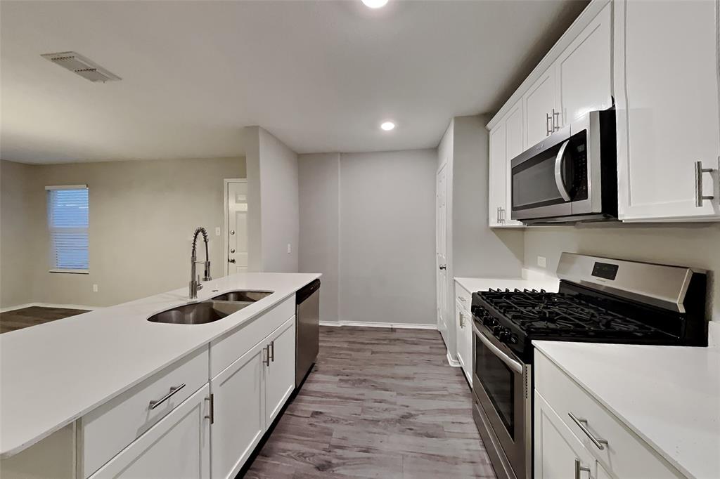 5529 McClelland Street Forney, TX 75126 - Photo 4 of 16 a kitchen with stainless steel appliances granite countertop white cabinets and stove