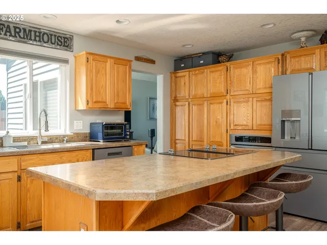 a kitchen with stainless steel appliances granite countertop a sink a stove and white cabinets with wooden floor