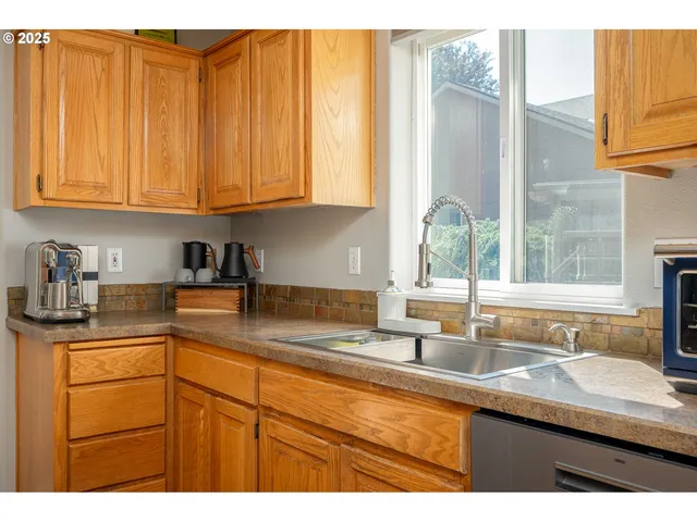 a kitchen with stainless steel appliances granite countertop a sink a window and cabinets