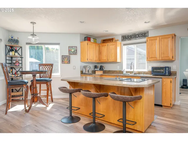 a kitchen with stainless steel appliances granite countertop a stove a sink a refrigerator and chairs
