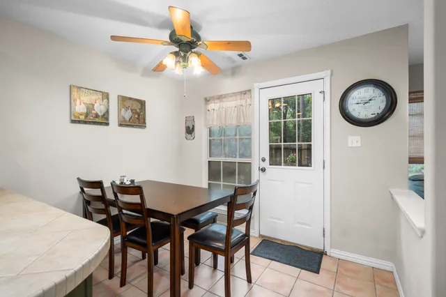a view of a dining room and kitchen with furniture a ceiling fan and wooden floor