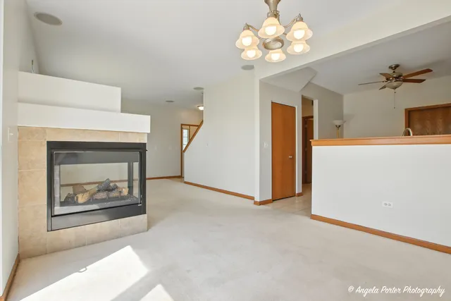 a view of a room with a chandelier fan and a fireplace