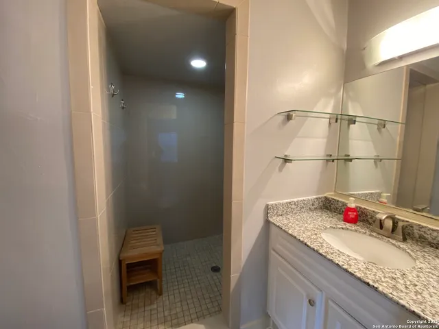 a bathroom with a granite countertop sink and a mirror