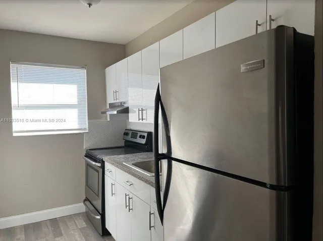 a kitchen with metallic refrigerator and white cabinets