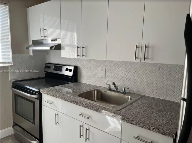 a kitchen with stainless steel appliances granite countertop a sink stove and white cabinets