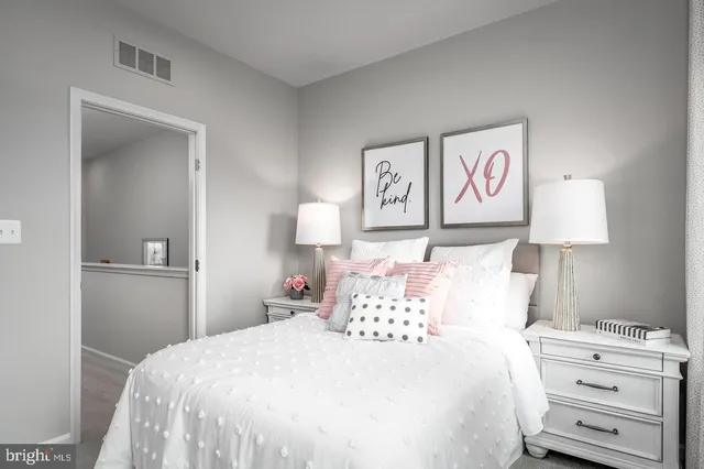 a bedroom with a bed and a lamp on dresser