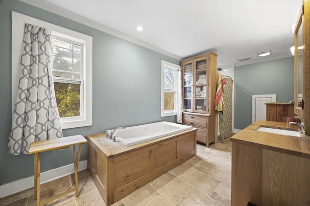 a spacious bathroom with a tub sink and mirror