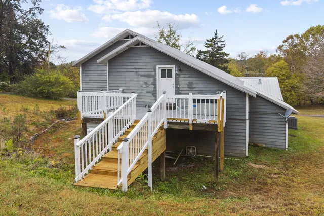 a view of house with a yard and deck