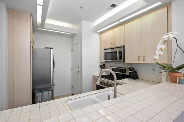 a bedroom with a bed a flat tv screen and a lamp on dresser